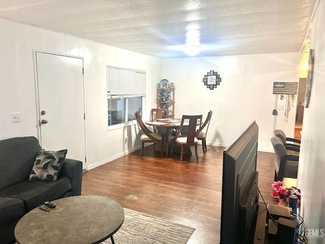 interior space featuring a textured ceiling, wood finished floors, and baseboards