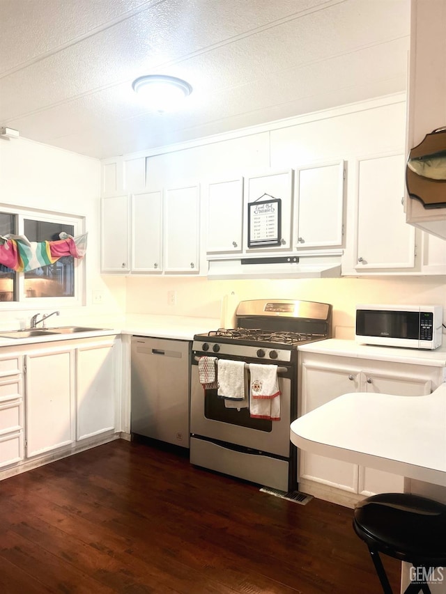 kitchen with dark wood-style floors, stainless steel appliances, a sink, and light countertops