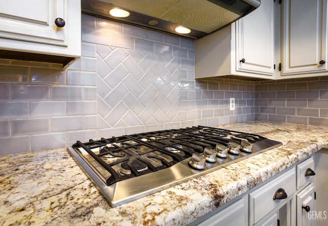 9604 Lea Oak Rd, Bakersfield, CA 93311 - kitchen view of stainless steel gas stovetop, under cabinet range hood, decorative backsplash, white cabinets, and light stone countertops