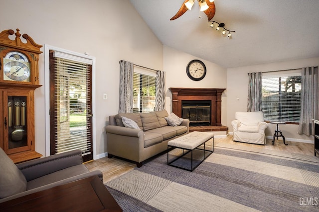 9604 Lea Oak Rd, Bakersfield, CA 93311 - living area with vaulted ceiling, wood finished floors, a glass covered fireplace, a ceiling fan, and baseboards