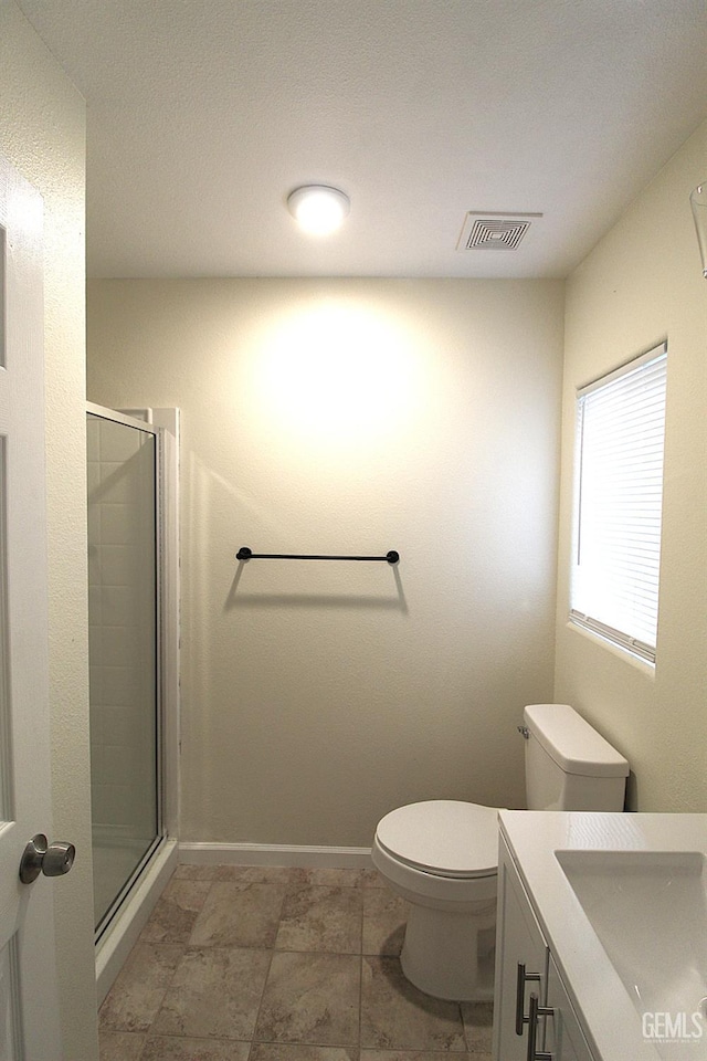 full bathroom featuring vanity, baseboards, a stall shower, toilet, and visible vents