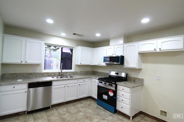 kitchen featuring visible vents, white cabinets, a sink, stainless steel appliances, and light stone counters