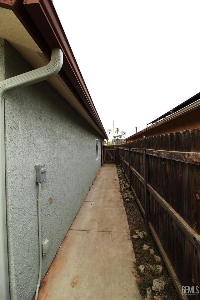 view of side of property with stucco siding and fence