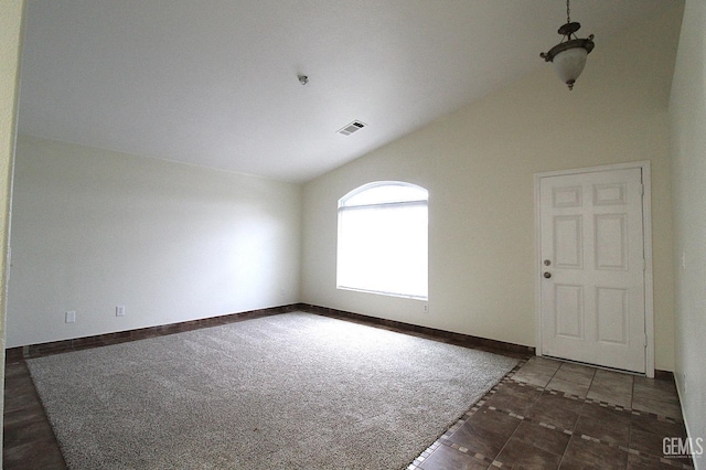 tiled spare room with visible vents, baseboards, and vaulted ceiling