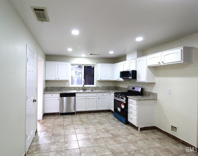 kitchen featuring baseboards, white cabinets, visible vents, appliances with stainless steel finishes, and a sink