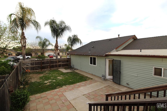 back of house featuring a shingled roof, a patio area, and a fenced backyard