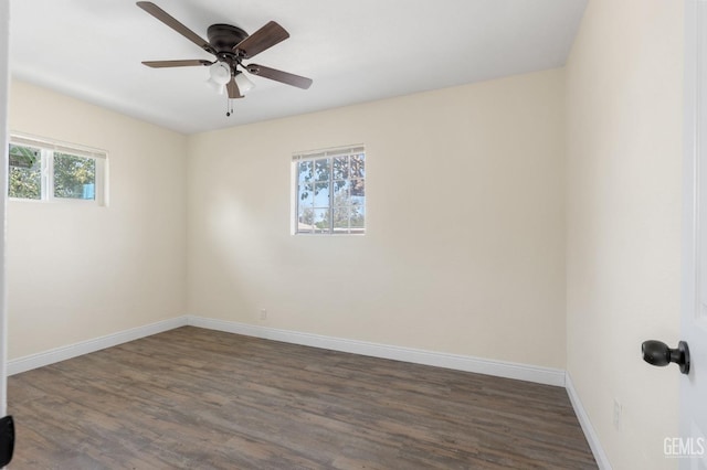 spare room featuring dark hardwood / wood-style floors, ceiling fan, and a healthy amount of sunlight