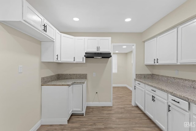 kitchen with white cabinetry, light stone counters, and light hardwood / wood-style floors