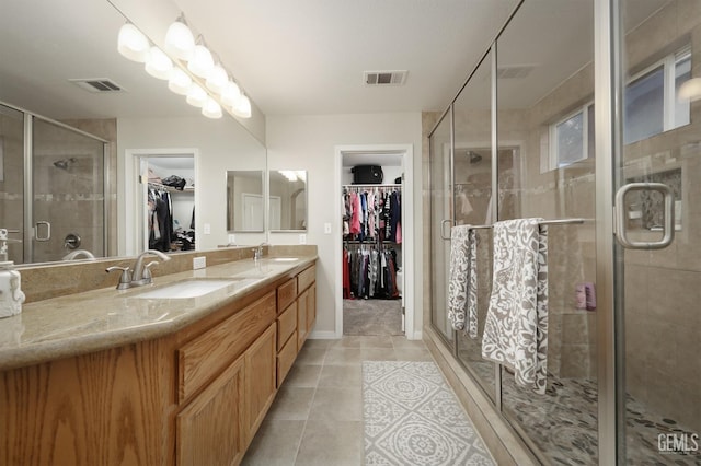 bathroom with a stall shower, visible vents, a sink, and tile patterned floors