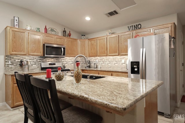 kitchen with lofted ceiling, light tile patterned flooring, a sink, appliances with stainless steel finishes, and light brown cabinetry