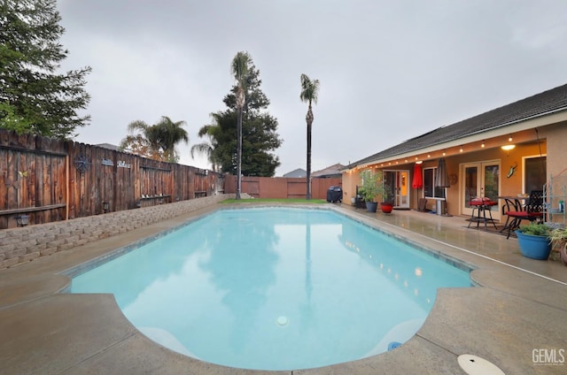 view of swimming pool featuring a fenced backyard, a grill, french doors, a fenced in pool, and a patio area