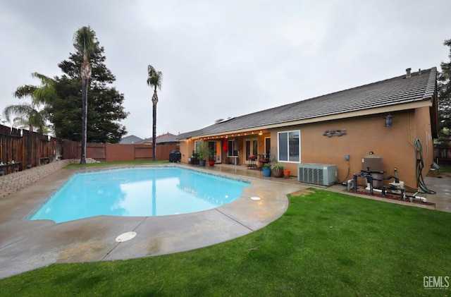 view of swimming pool featuring a fenced in pool, a yard, central AC, a patio area, and a fenced backyard