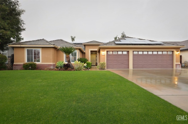 prairie-style house with driveway, solar panels, an attached garage, a front lawn, and brick siding