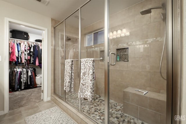 bathroom featuring a stall shower, tile patterned flooring, a walk in closet, and visible vents