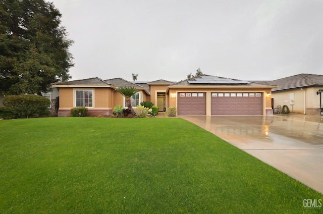 prairie-style house featuring driveway, solar panels, stucco siding, an attached garage, and a front yard