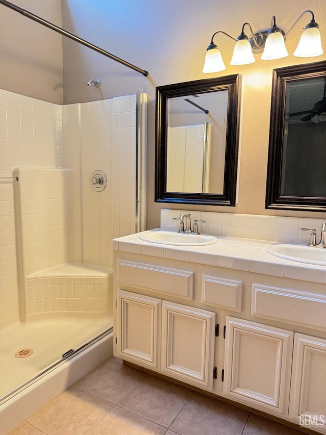 bathroom featuring tile patterned flooring, a sink, a shower stall, and double vanity