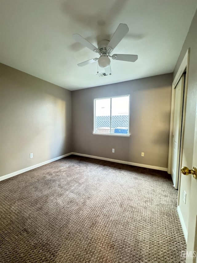 carpeted empty room featuring visible vents, ceiling fan, and baseboards