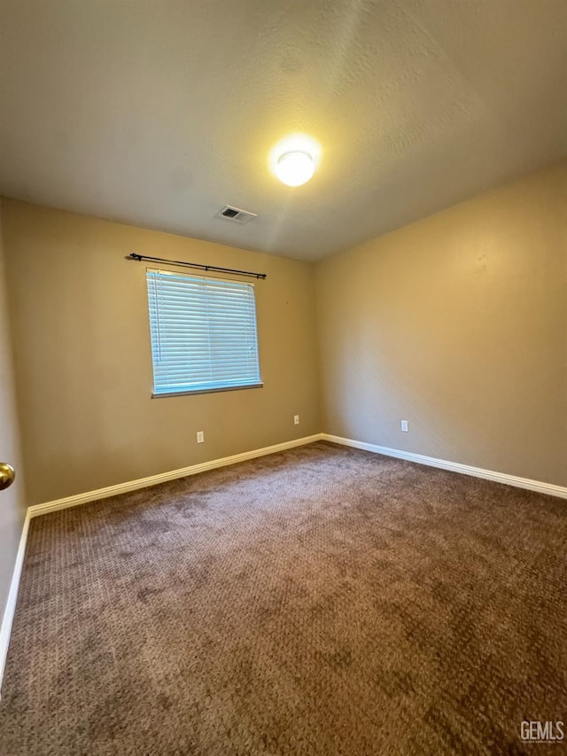 spare room with a textured ceiling, carpet floors, visible vents, and baseboards