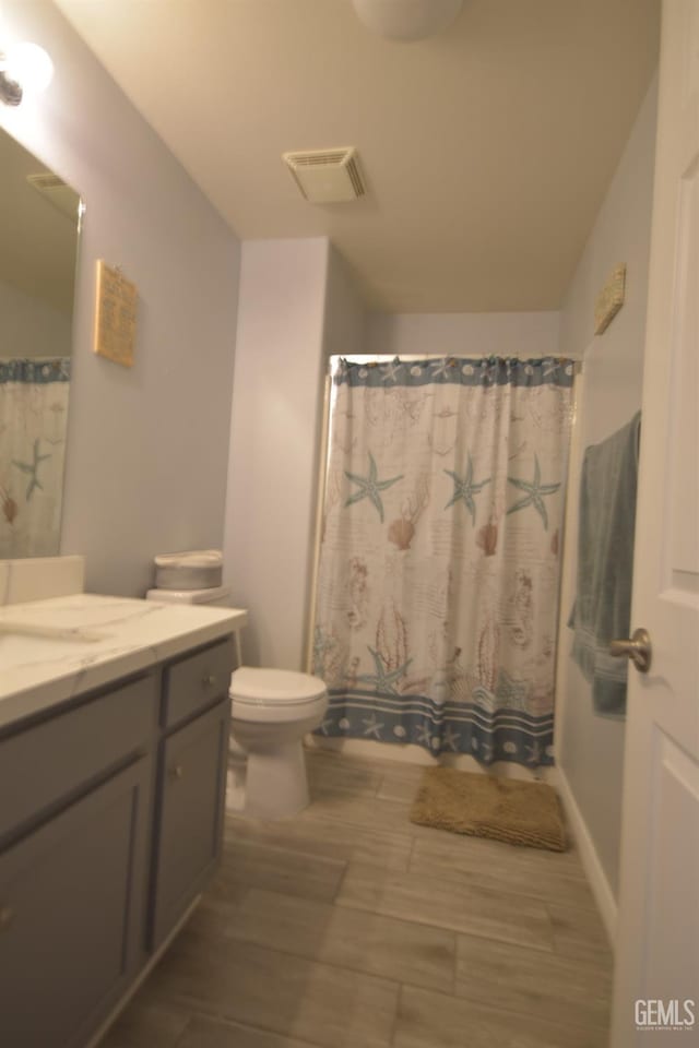 bathroom with a shower with shower curtain, hardwood / wood-style floors, vanity, and toilet