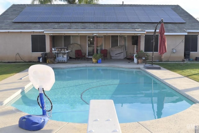 view of pool with a patio and a diving board