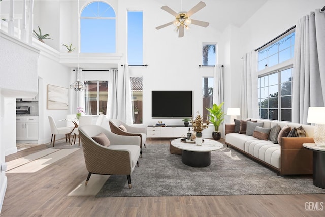 living room with ceiling fan, light hardwood / wood-style flooring, and a towering ceiling