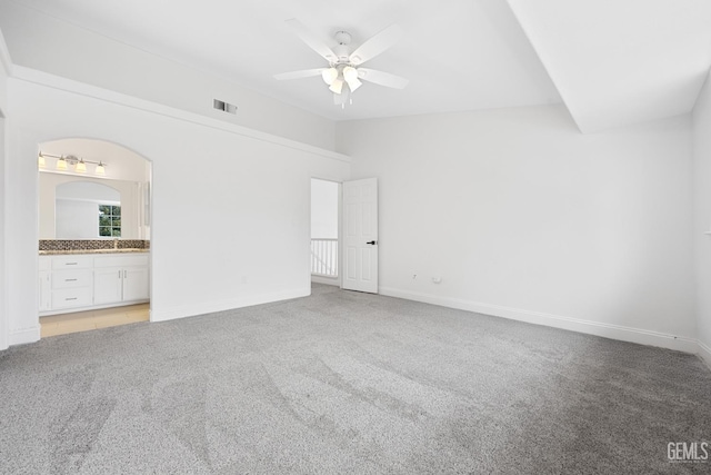 unfurnished bedroom featuring light carpet, ceiling fan, vaulted ceiling, and connected bathroom