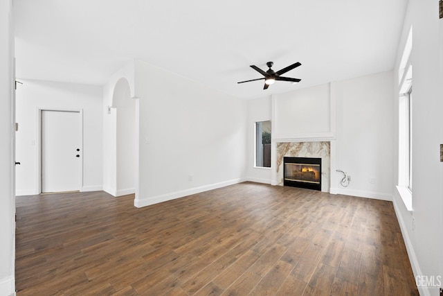 unfurnished living room with a fireplace, ceiling fan, and dark hardwood / wood-style flooring