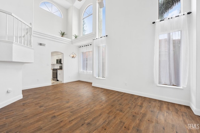 unfurnished living room with dark wood-type flooring and a towering ceiling