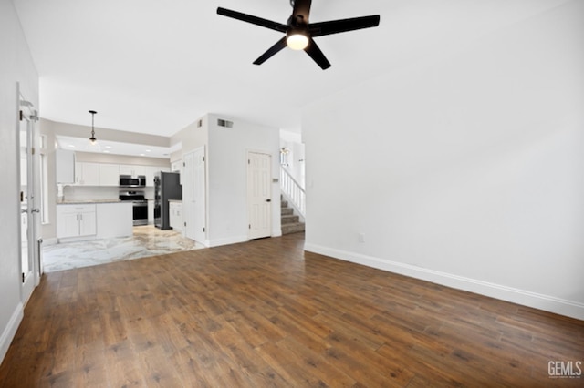 unfurnished living room featuring dark hardwood / wood-style flooring, ceiling fan, and sink