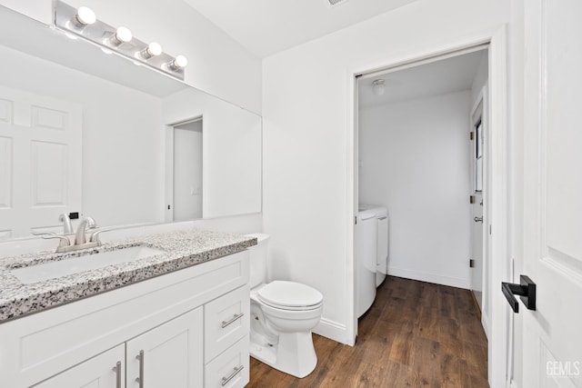 bathroom featuring hardwood / wood-style flooring, washer and clothes dryer, vanity, and toilet