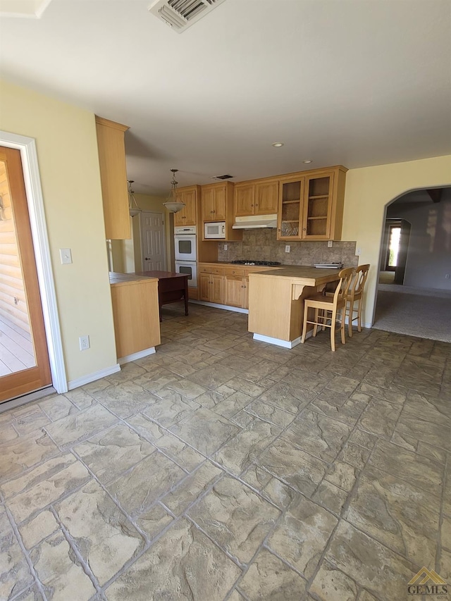 kitchen featuring pendant lighting, a kitchen breakfast bar, white appliances, and kitchen peninsula