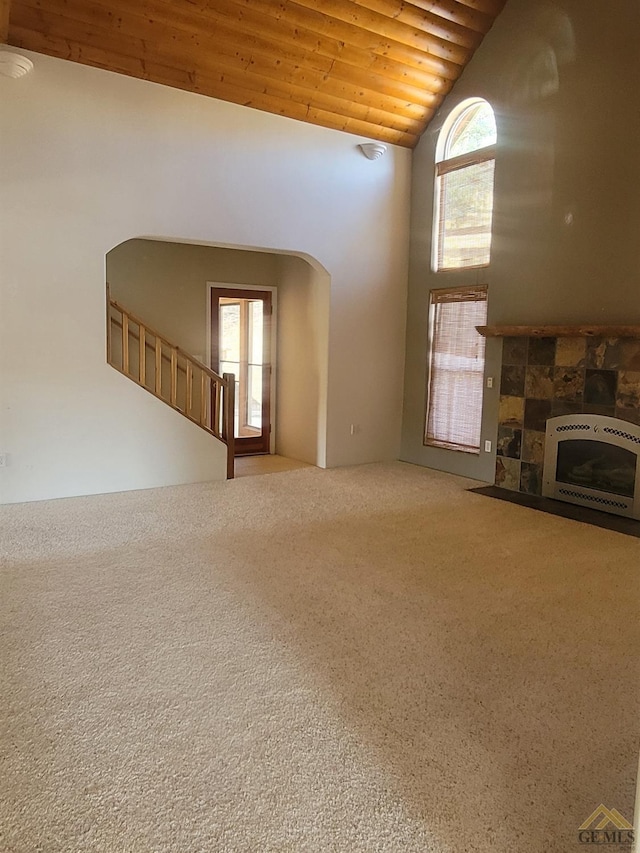 unfurnished living room with carpet, wood ceiling, heating unit, a tile fireplace, and lofted ceiling