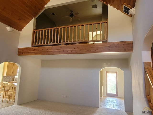 stairs featuring carpet, ceiling fan, and a towering ceiling