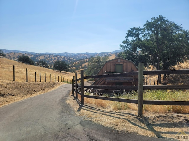 view of gate with a mountain view, a rural view, and an outbuilding