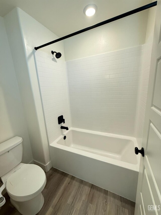 full bath with wood finished floors, toilet, and washtub / shower combination