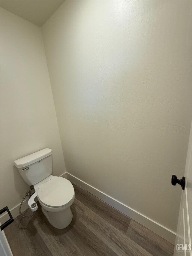 bathroom featuring wood finished floors, baseboards, and toilet