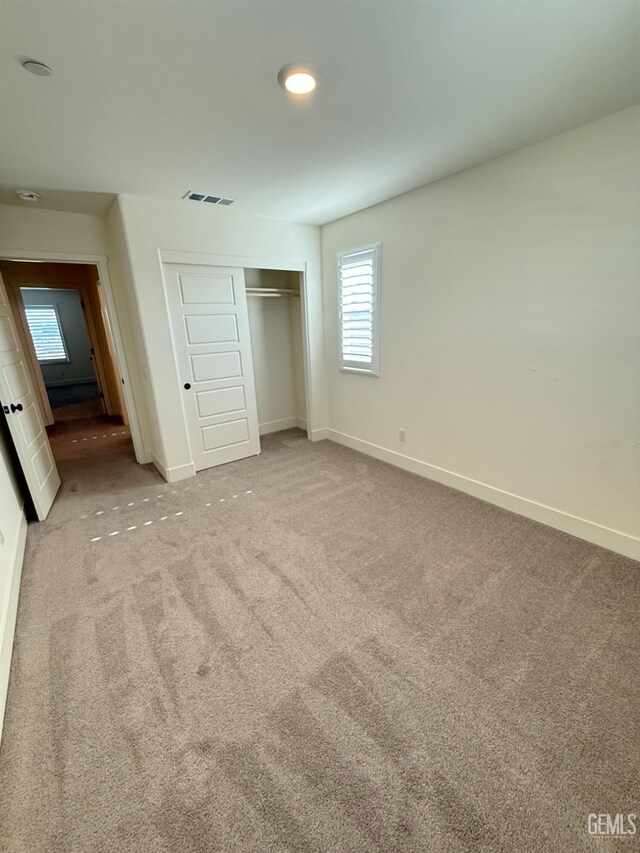 unfurnished bedroom featuring carpet, baseboards, and a closet