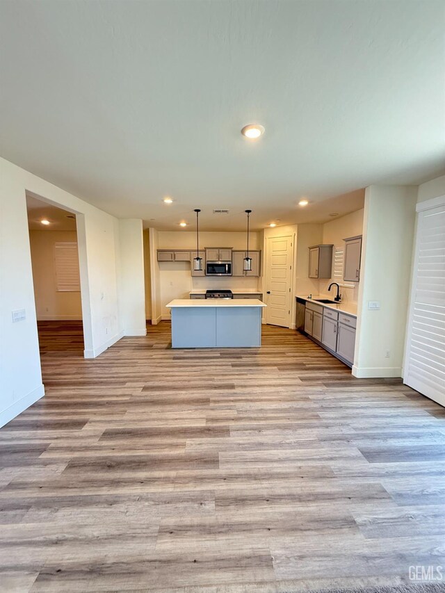kitchen featuring stainless steel microwave, gray cabinetry, baseboards, light wood-style floors, and recessed lighting