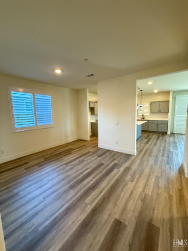 unfurnished living room with baseboards, wood finished floors, and recessed lighting