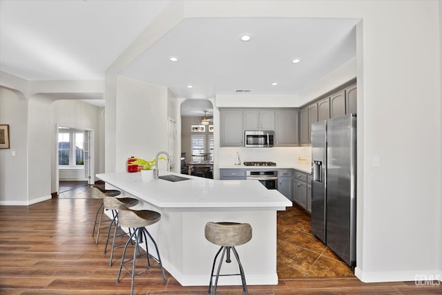 4504 Polo Club Dr, Bakersfield, CA 93312 - kitchen featuring stainless steel appliances, gray cabinetry, a breakfast bar, a peninsula, and light countertops