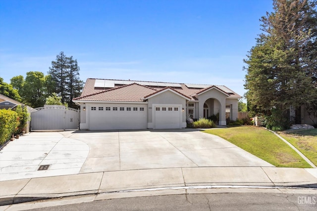 4504 Polo Club Dr, Bakersfield, CA 93312 - mediterranean / spanish-style house with a gate, a garage, a tiled roof, stucco siding, and roof mounted solar panels