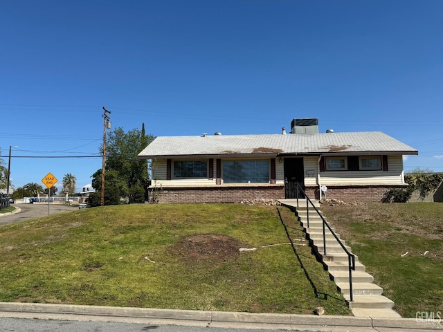 ranch-style home featuring stairway, central air condition unit, and a front lawn