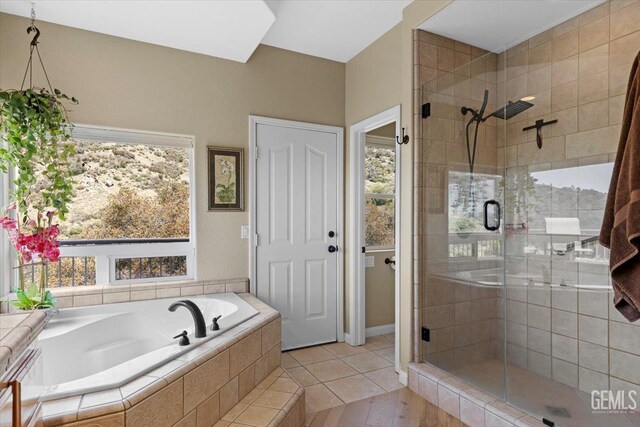 bathroom with a wealth of natural light, a garden tub, and a stall shower