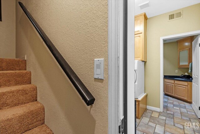 stairway featuring visible vents, baseboards, and stone tile flooring