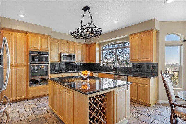 kitchen with light brown cabinetry, a center island, stone finish flooring, backsplash, and stainless steel appliances