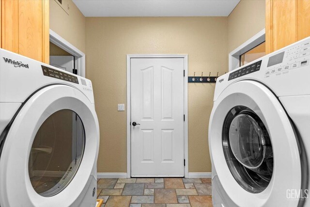 laundry room with stone finish floor, baseboards, cabinet space, and washer / clothes dryer