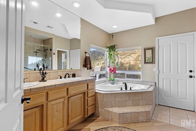 bathroom with a sink, double vanity, a shower stall, visible vents, and a garden tub
