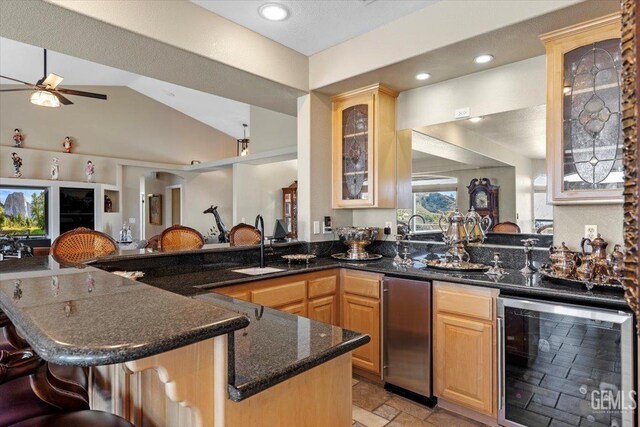 kitchen with light brown cabinetry, a kitchen breakfast bar, a ceiling fan, and beverage cooler