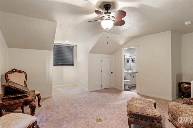 sitting room with lofted ceiling, light carpet, baseboards, ceiling fan, and a textured ceiling