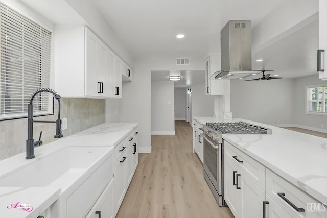 6405 Hesketh Dr, Bakersfield, CA 93309 - kitchen featuring high end range, a sink, island exhaust hood, decorative backsplash, and white cabinets